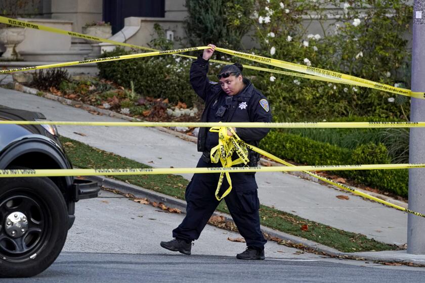 A police officer rolls out more yellow tape on the closed street below the home of House Speaker Nancy Pelosi and her husband Paul Pelosi in San Francisco, Friday, Oct. 28, 2022. Paul Pelosi, was attacked and severely beaten by an assailant with a hammer who broke into their San Francisco home early Friday, according to people familiar with the investigation. (AP Photo/Eric Risberg)