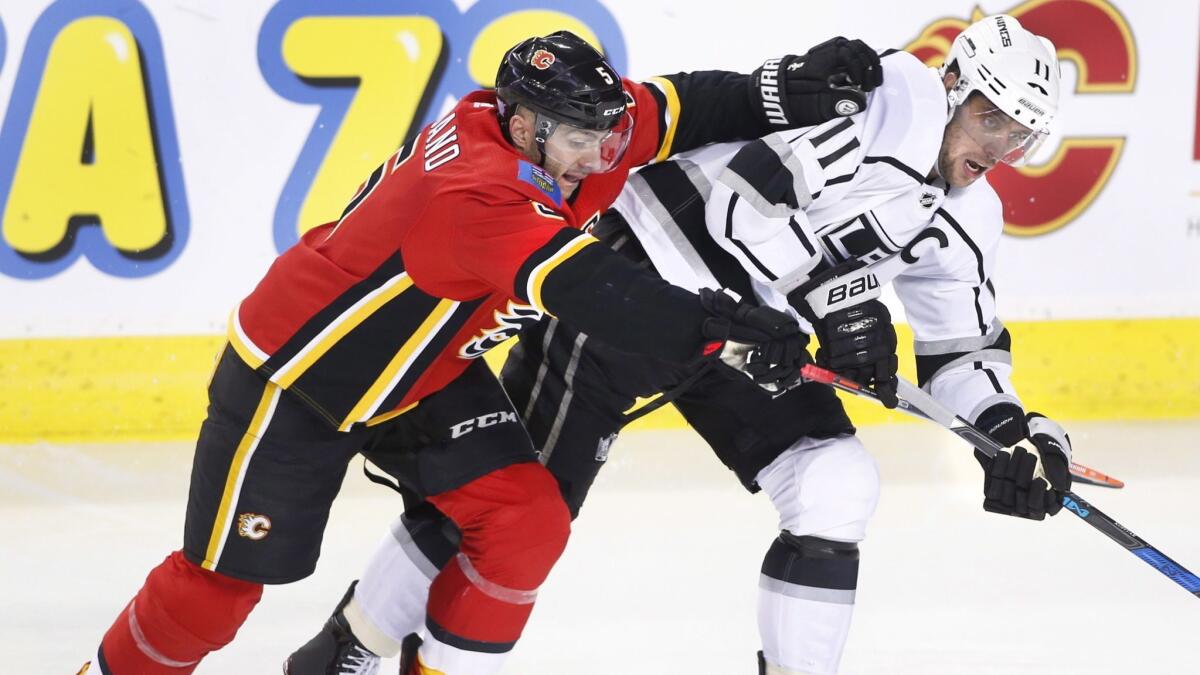 Kings center Anze Kopitar (11) and Calgary Flames defenseman Mark Giordano (5) battle for the puck during the second period.