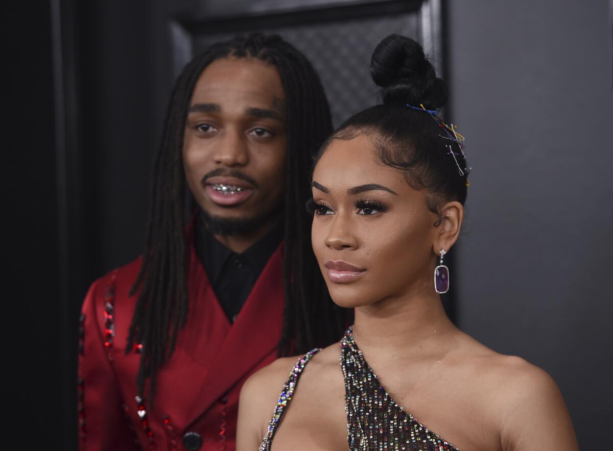Quavo in a red suit with Saweetie in a sparkling dress