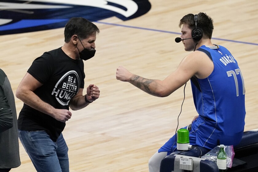 Dallas Mavericks team owner Mark Cuban, left, celebrates with Luka Doncic, right, as Doncic participates in a broadcast interview after their 118-117 win in an NBA basketball game against the Atlanta Hawks in Dallas, Wednesday, Feb. 10, 2021. (AP Photo/Tony Gutierrez)