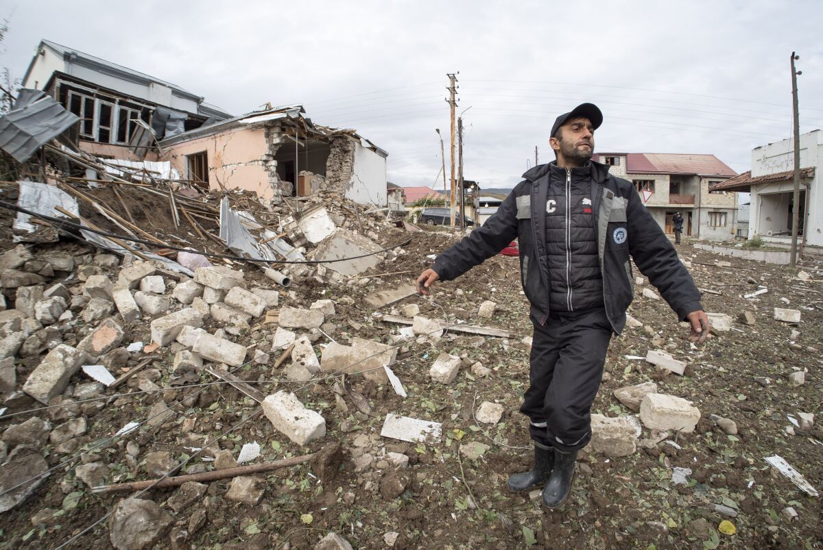 A man stands near the rubble of a house destroyed by shelling