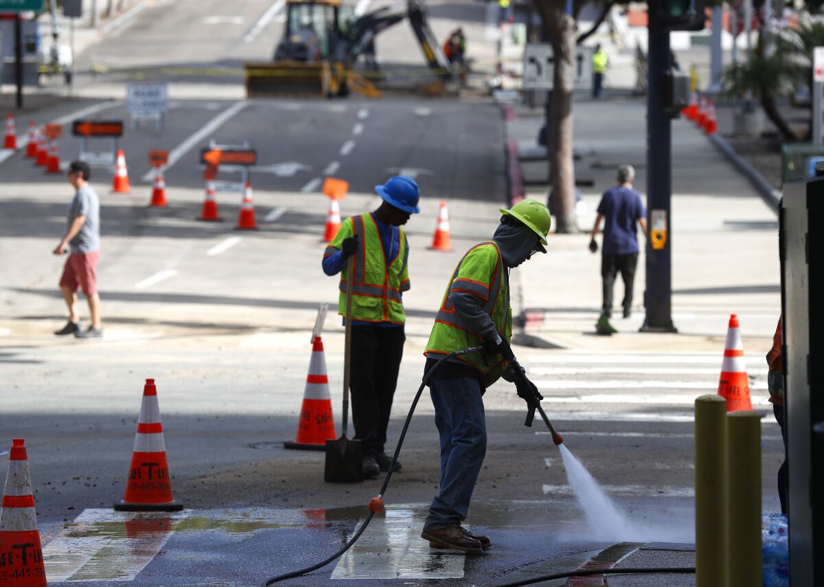 Crews power wash the street at A Street and 10th Ave. the day after a water main break on Monday, Nov. 22, 2021. 