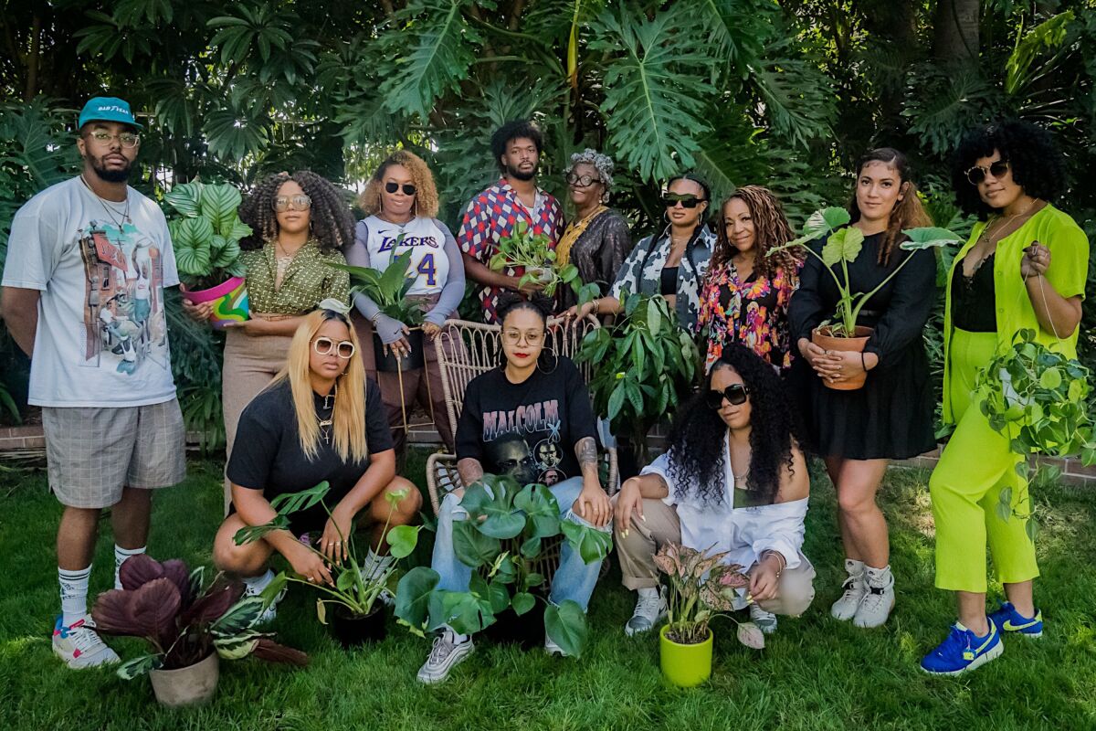 Twelve people pose for a photo with their houseplants.