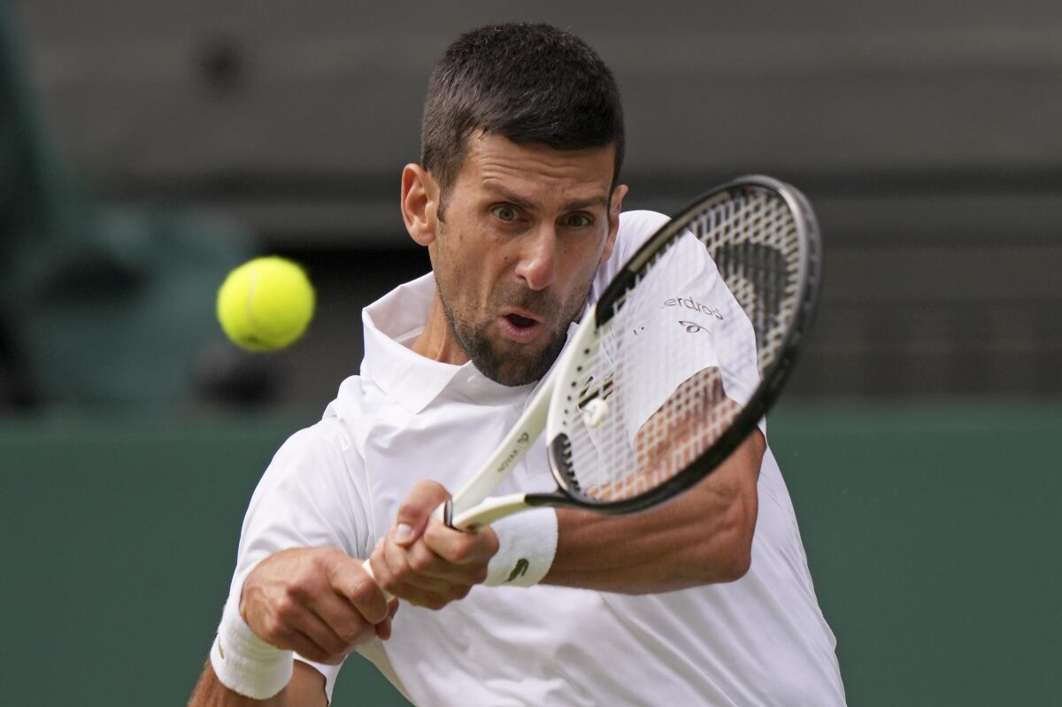 Novak Djokovic makes a backhanded return to Hubert Hurkacz during their Wimbledon match on Monday.