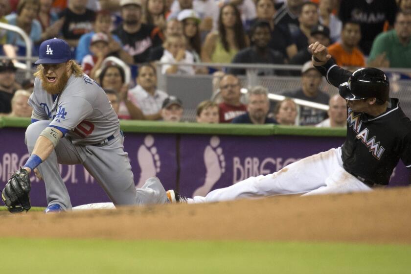 Dodgers third baseman Justin Turner (misses the ball as Miami's Christian Yelich slides into third.