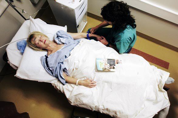 One of the nurses at the surgery center tries to find a vein in reporter Martha Groves' hand for the IV drip. It is painful, and Groves tries to relax in anticipation of it.