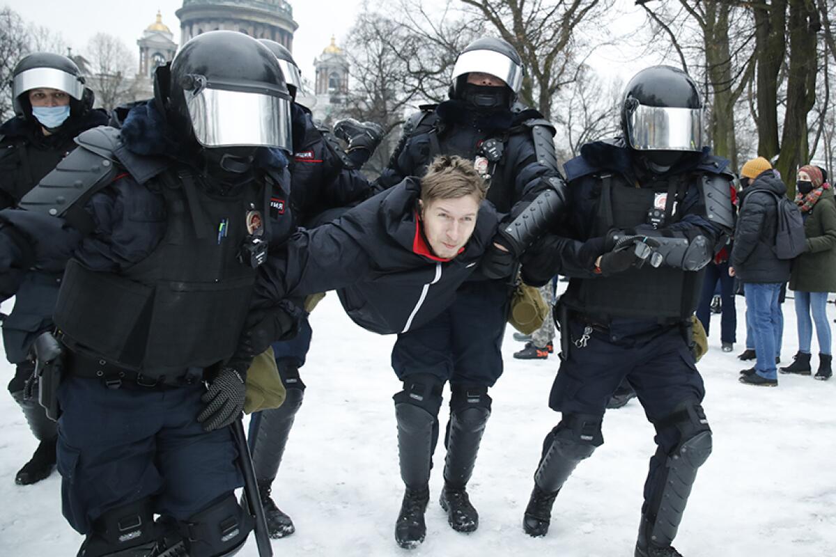 A man is detained by law enforcement outside in the snow.