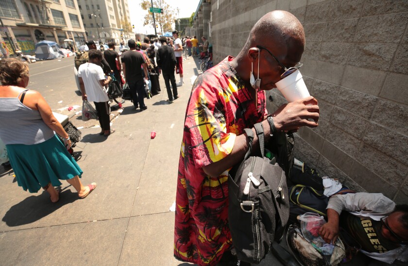 Stafford Wilson, 50, left, shares Ginger Ale with a friend outside The Midnight Mission in Downtown Los Angeles.