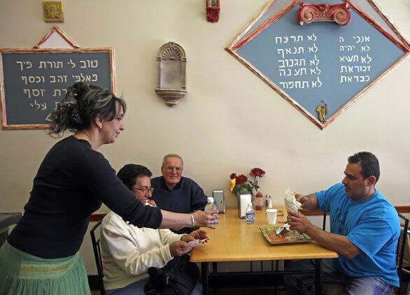 Shawarma made the Israeli way is the specialty at Shawarma Palace in Pico Boulevard's kosher corridor. Ayala Sherf, left, runs the restaurant with husband Pinchas. Here she makes a delivery to a tableful of customers.