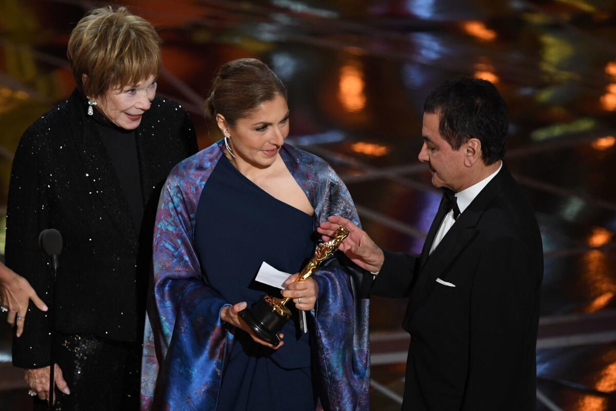 Anousheh Ansari, center, accepts the Oscar for foreign language film on behalf of Iranian director Asghar Farhadi, who boycotted the ceremony in protest of President Trump's immigration policies.