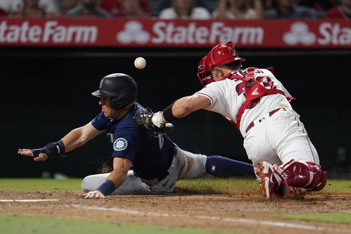 Seattle Mariners' Dylan Moore scores past Angels catcher Max Stassi.