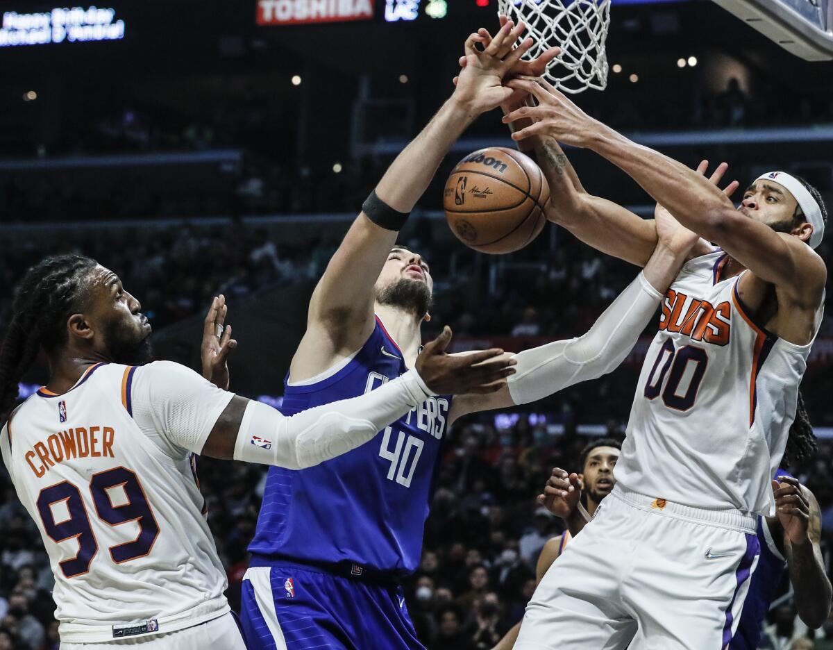 Clippers center Ivica Zubac battles Phoenix Suns center JaVale McGee and forward Jae Crowder for a rebound.