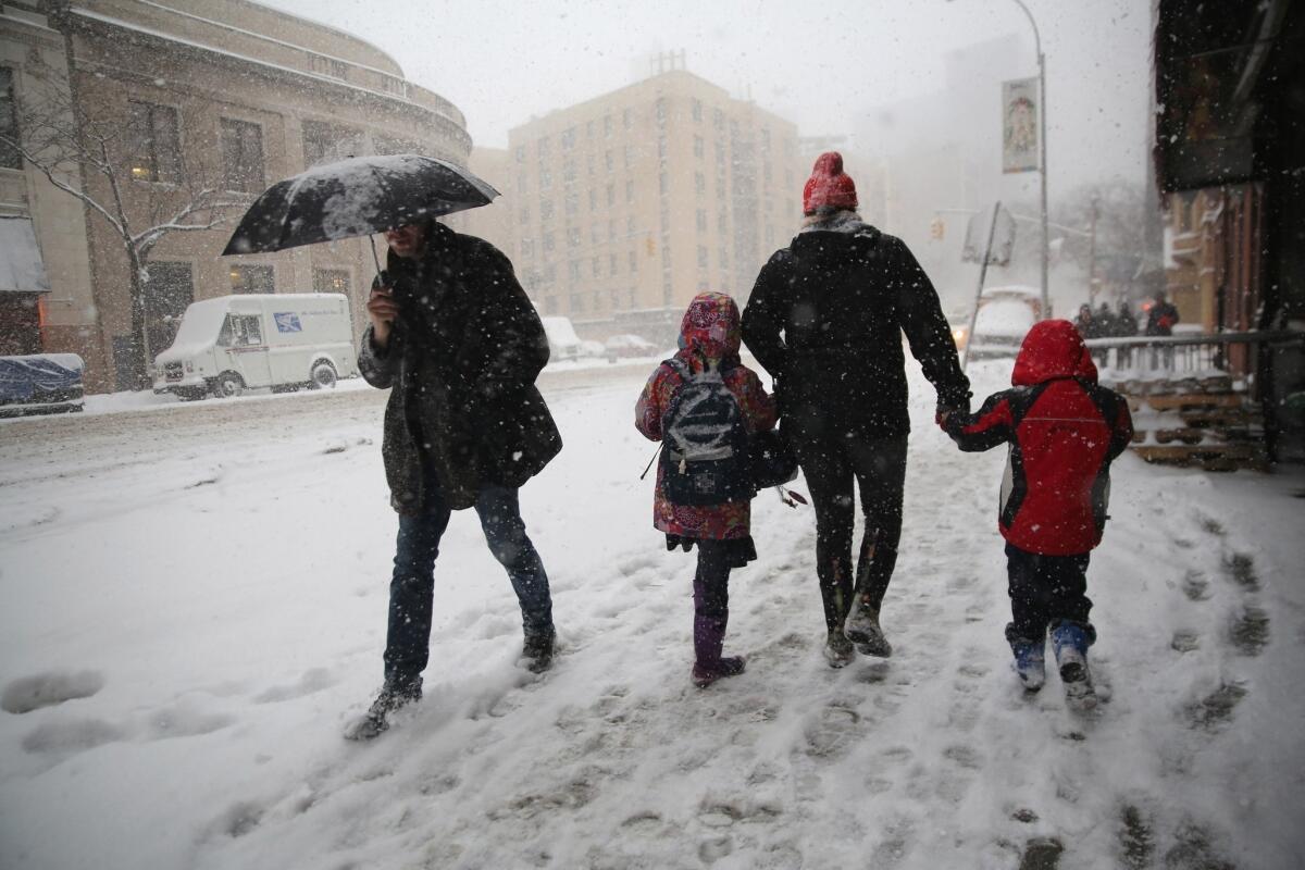 A person walks two kids to school during a snowstorm on Thursday in New York City.