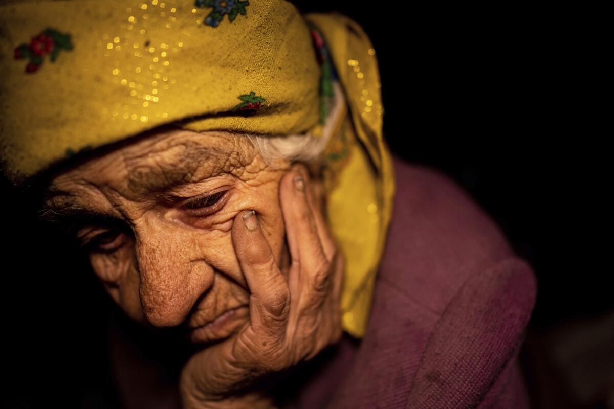Nina Gonchar, 93, sits with her head resting on her hand in the dark.