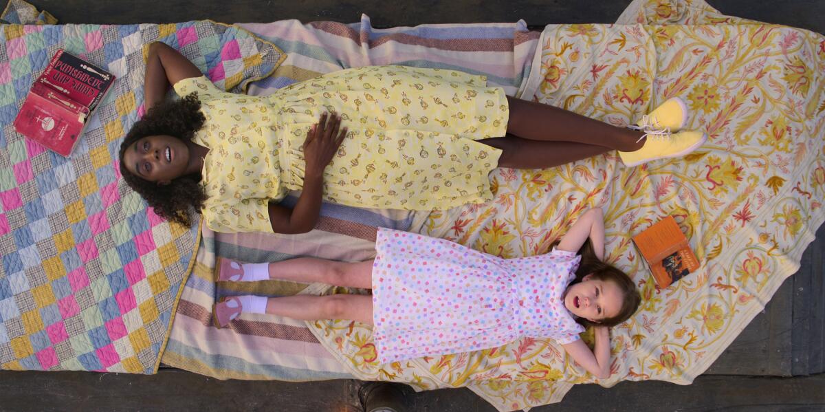 A woman and girl laying on the ground side by side.