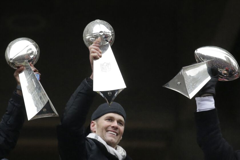 FILE - Then-New England Patriots quarterback Tom Brady holds a Super Bowl trophy, between others the team previously had won, during a rally in Boston to celebrate the team's 34-28 win over the Atlanta Falcons in the NFL Super Bowl 51 football game in Houston, Feb. 7, 2017. The seven-time Super Bowl champion is enjoying retirement while staying busy. He’s preparing for his new 2024 broadcasting gig at Fox Sports, is set to become a minority owner of the Las Vegas Raiders, and is focusing on his apparel and wellness brands. (AP Photo/Elise Amendola, File)