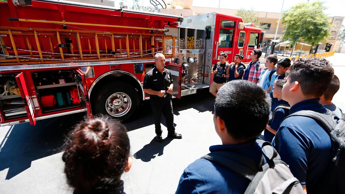 Los Angeles Fire Capt. Eddie Marez explains the workings of a fire engine to students at the new Wilson High School Firefighter Academy Magnet.