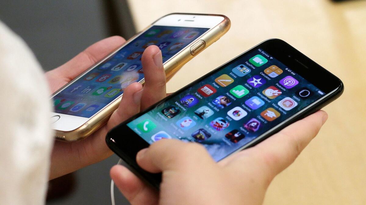 A customer compares a jet black iPhone 7, right, with her iPhone 6 at the Apple Store in Chicago, Ill. on Sept. 16, 2016.