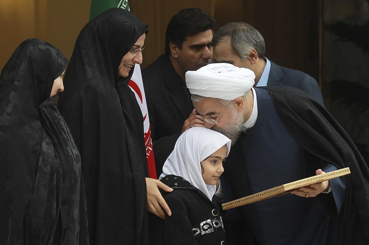 Iran President Hassan Rouhani kisses the head of the daughter of a slain nuclear researcher at a news conference Sunday.