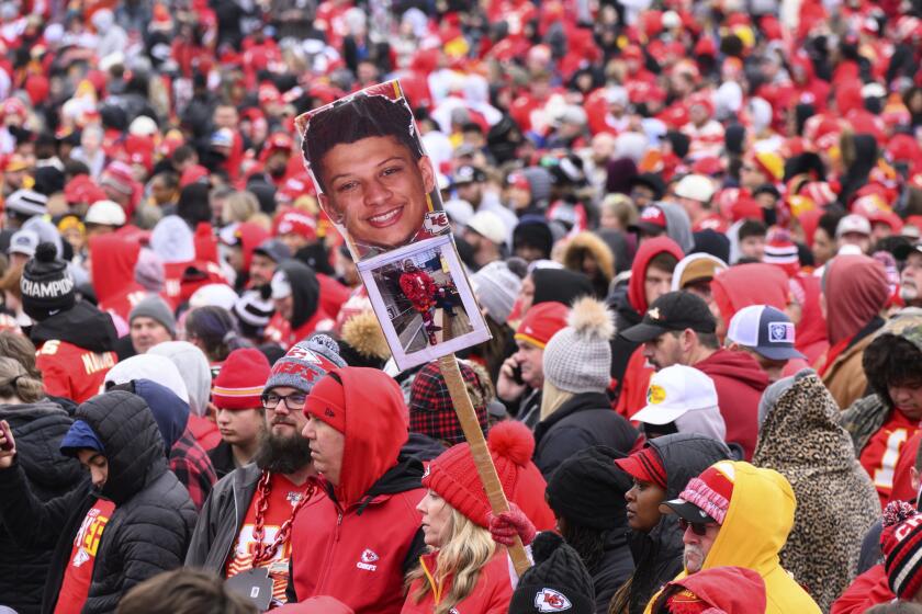 A fan waves a sign with Patrick Mahomes' photo on it during the Kansas City Chiefs' victory celebration and parade