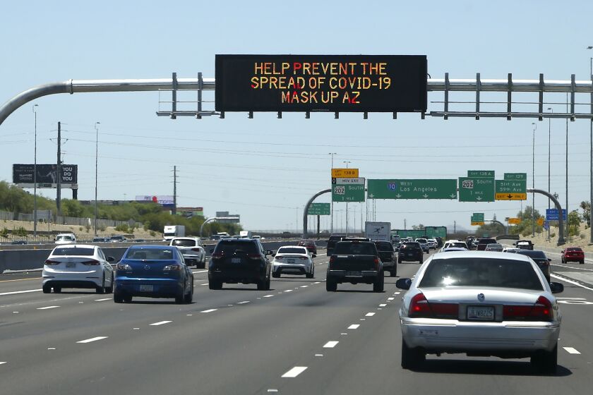 The Arizona Department of Transportation posts new signage along highways urging the public to wear face coverings due to the recent surge in coronavirus cases Sunday, June 21, 2020, in Phoenix. (AP Photo/Ross D. Franklin)