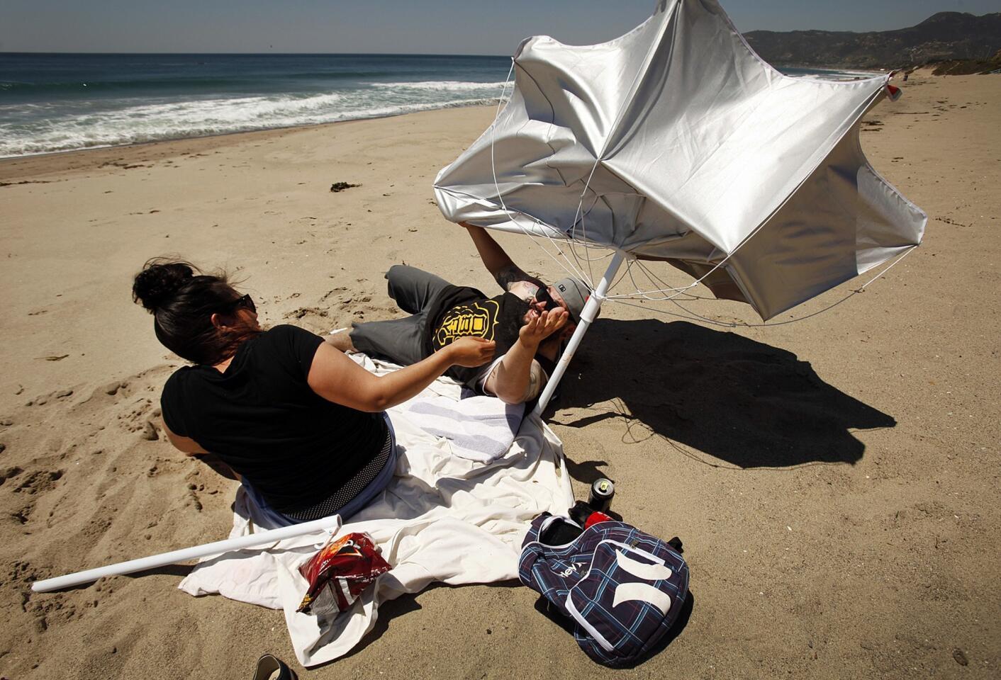 Jerry Gallo, 27, and girlfriend Maxie Guillen, 26, of Pacoima try in vain to keep their shade umbrella in place in the wind at Westward Beach in Malibu.