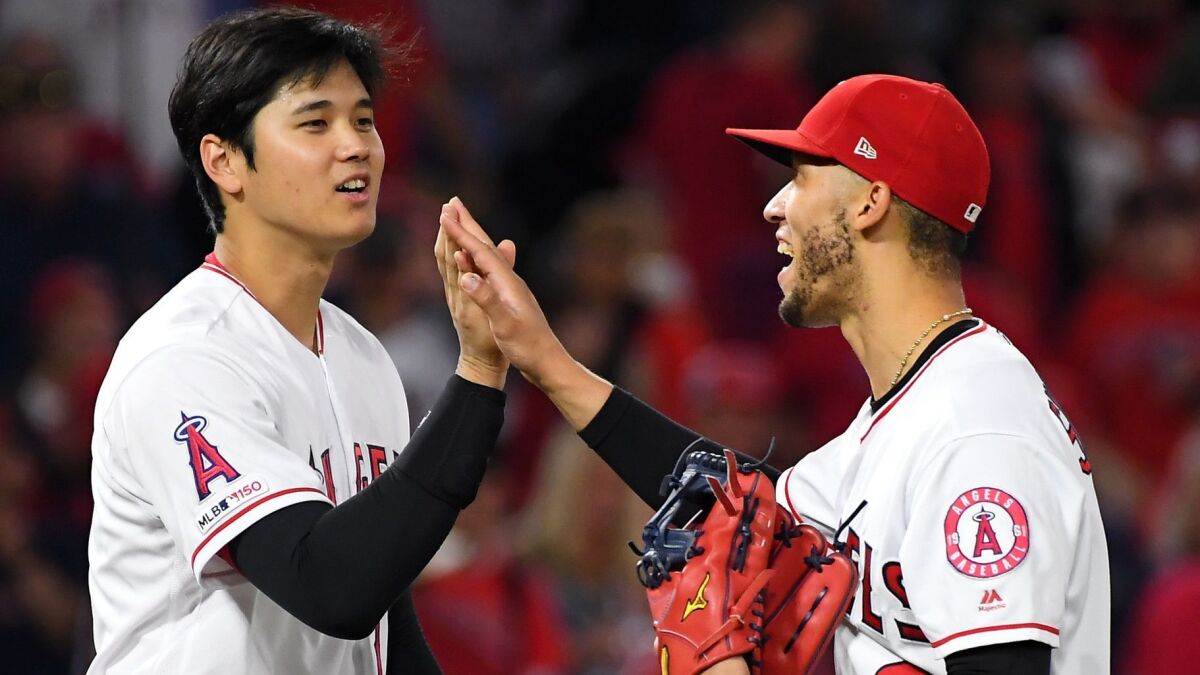 Angels' Shohei Ohtani, left, gives a high five to Andrelton Simmons after the final out against the Oakland Athletics at Angel Stadium on Thursday.