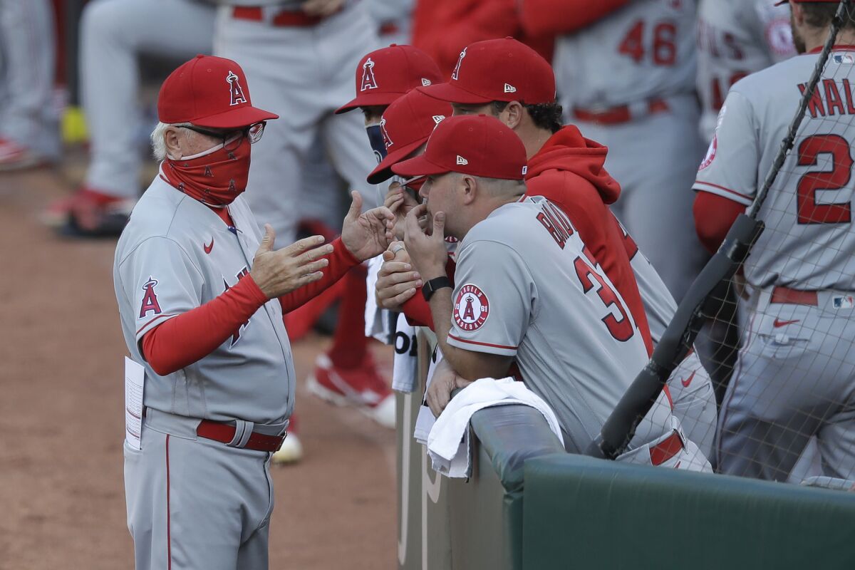 Angels manager Joe Maddon, left, talks with his team before its game against the Athletics on July 24, 2020.