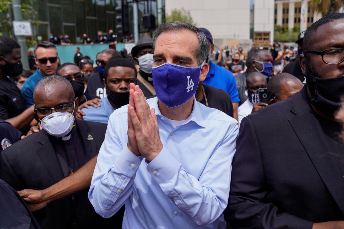 L.A. Mayor Eric Garcetti puts his hands together in a gesture of prayer with protesters and clergy in downtown Los Angeles. 