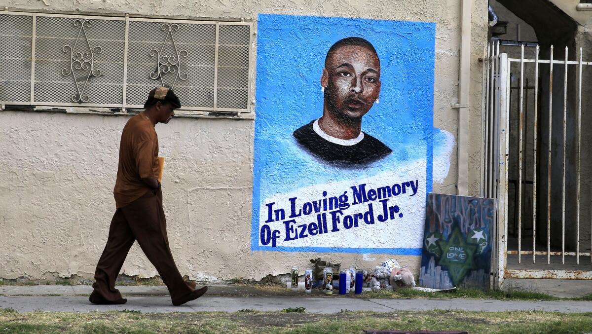 A man walks by a memorial at 65th Street and Broadway in South L.A., where Ezell Ford was killed.