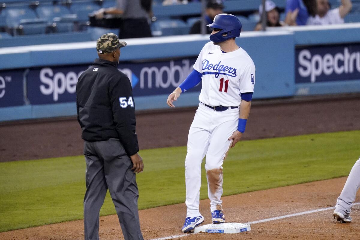 Dodgers baserunner AJ Pollock grabs the back of his left leg after sliding into third on a double by Austin Barnes.