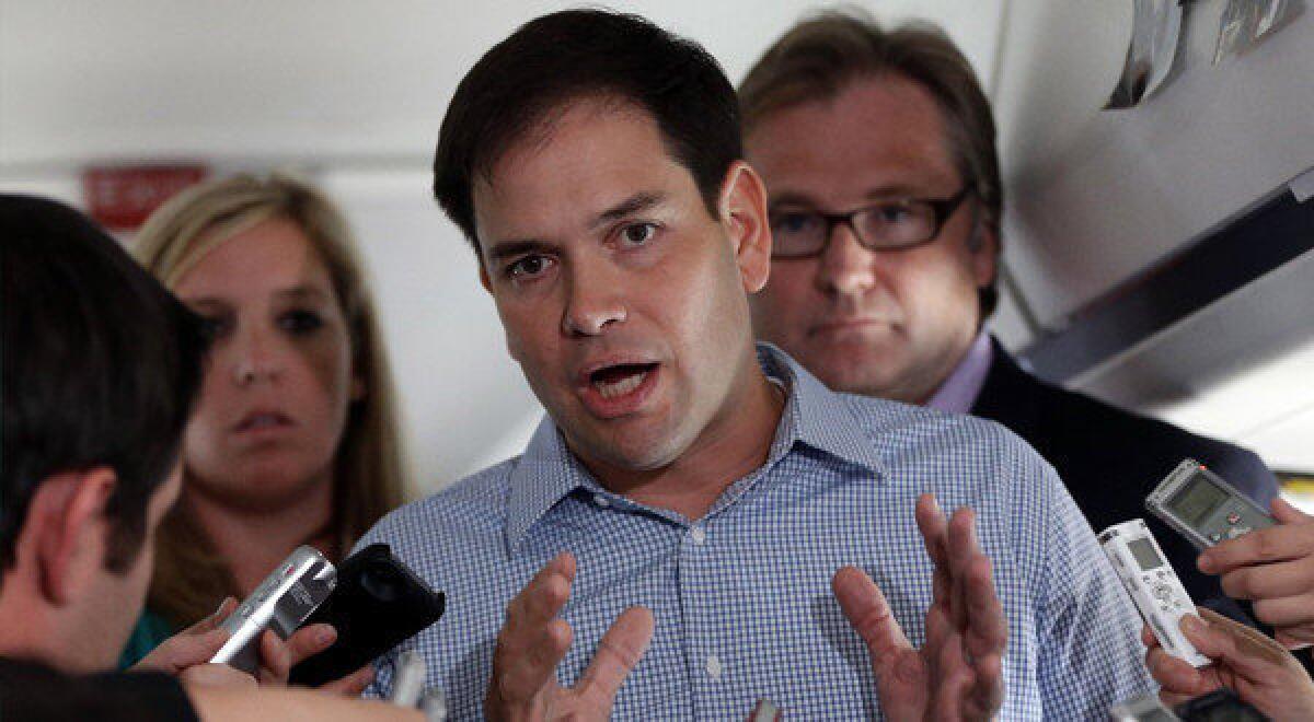 Sen. Marco Rubio (R-Fla.) who is traveling with Republican presidential candidate Mitt Romney, speaks to reporters on Romney's campaign plane en route to Orlando, Fla.