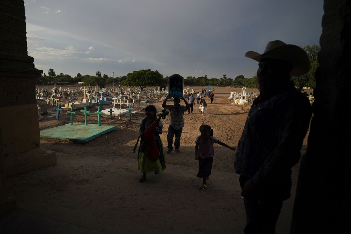 Indigenous family walking past a cemetery in Potam, Mexico
