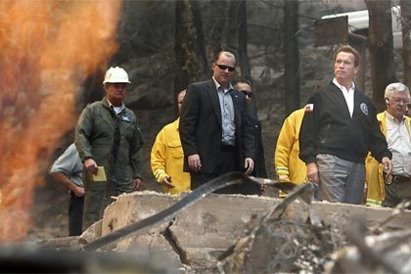 OMNIPRESENT: Gov. Arnold Schwarzenegger tours the scorched area along Brentwood Drive in Lake Arrowhead on Tuesday. He has been on nearly nonstop visits to fire-afflicted areas since Monday.
