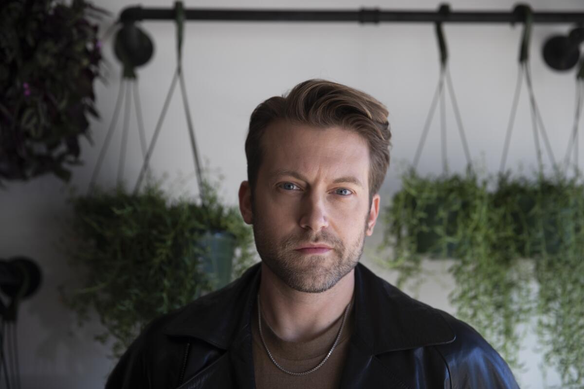 A portrait of Long Beach Opera's James Darrah amid hanging plants.