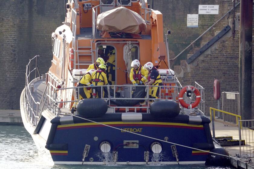 Members of the Dover lifeboat place a body bag on a stretcher after returning to the Port of Dover after a large search and rescue operation launched in the Channel off the coast of Dungeness, in Kent, Wednesday Dec. 14, 2022, following an incident involving a small boat likely to have been carrying migrants. Helicopters and lifeboats have been dispatched to the English Channel off the coast of Kent in southern England to rescue a small boat in distress, authorities said Wednesday. (Gareth Fuller/PA via AP)