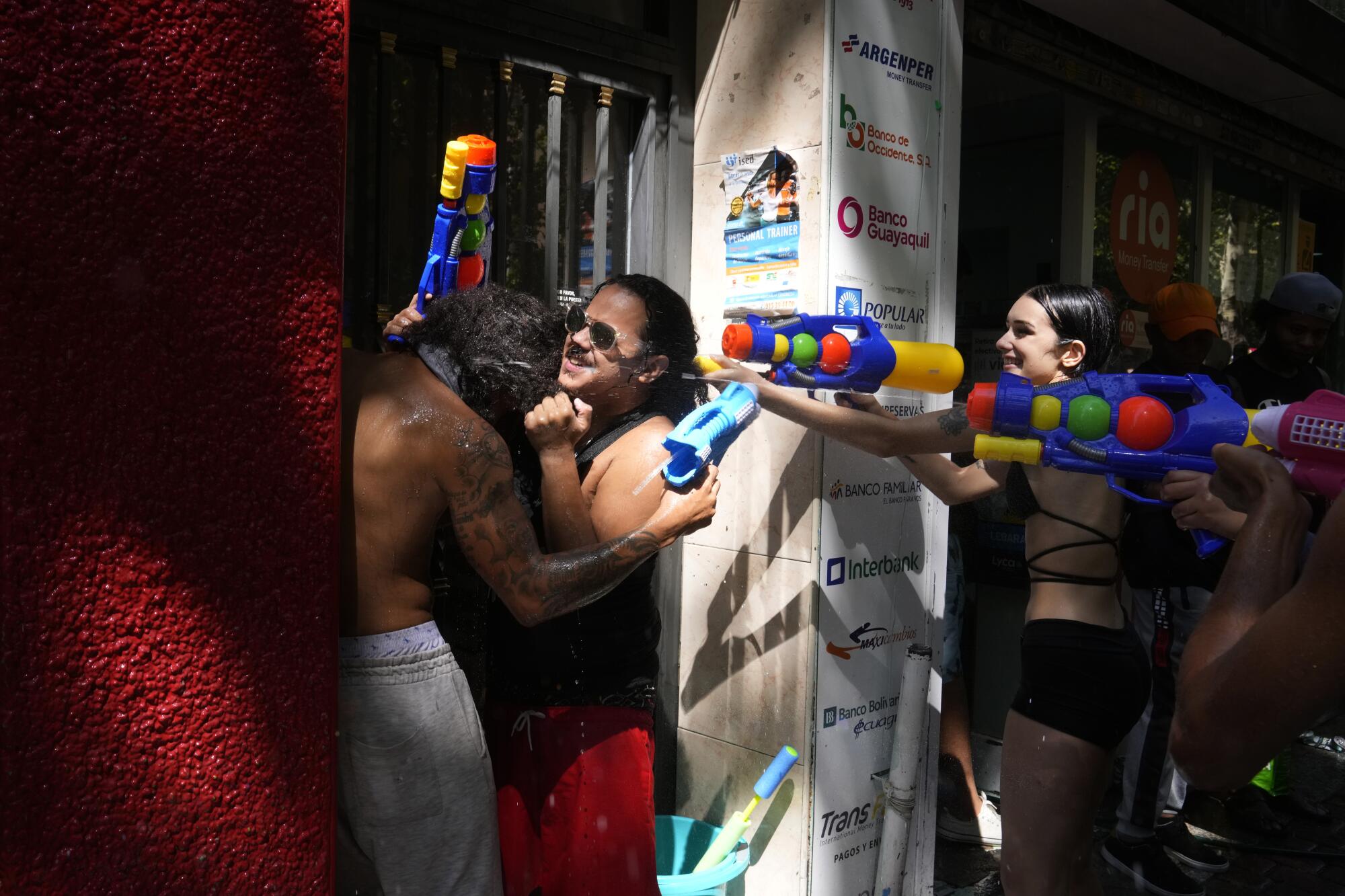 Two men shelter in a doorway as others spray water pistols during a water fight