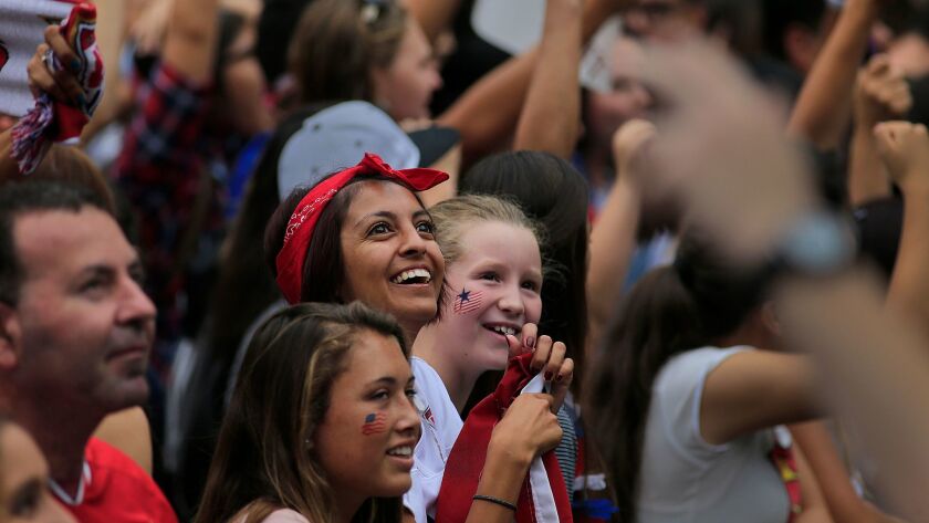 Soccer fans watch the big screen as the 2015 United States Women's National Soccer Team takes the stage after winning the FIFA Women's World Cup at a free, public championship celebration in Los Angeles, Calif. on July 7, 2015.