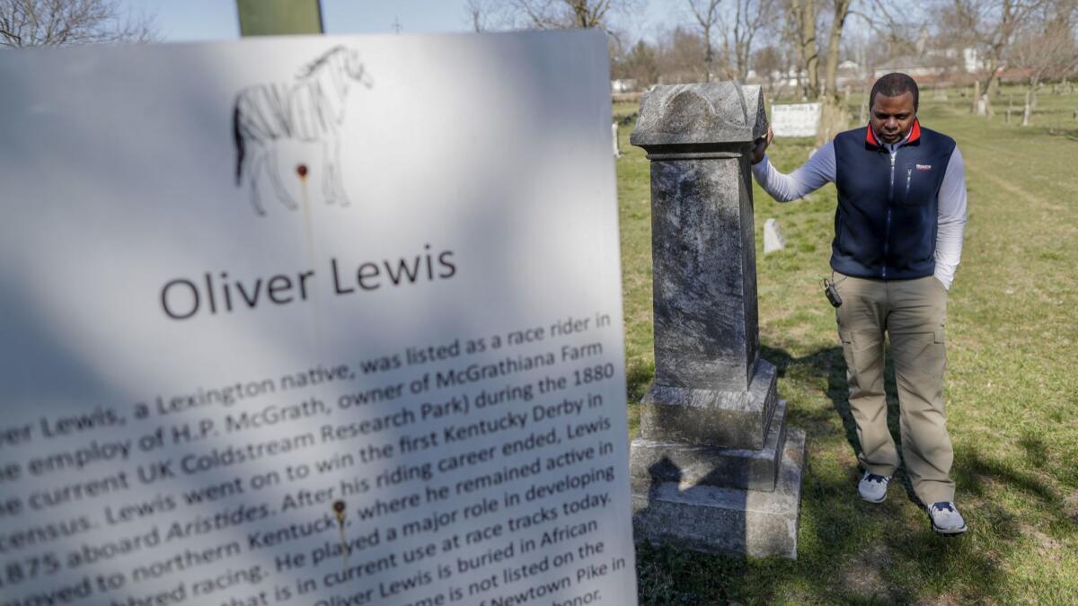 Leon Nichols, a founder of Project to Preserve African-American Turf History, stands next to the headstone for the family of jockey Oliver Lewis at African Cemetery No. 2, located on a small lot in a suburban neighborhood in Lexington, Ky.