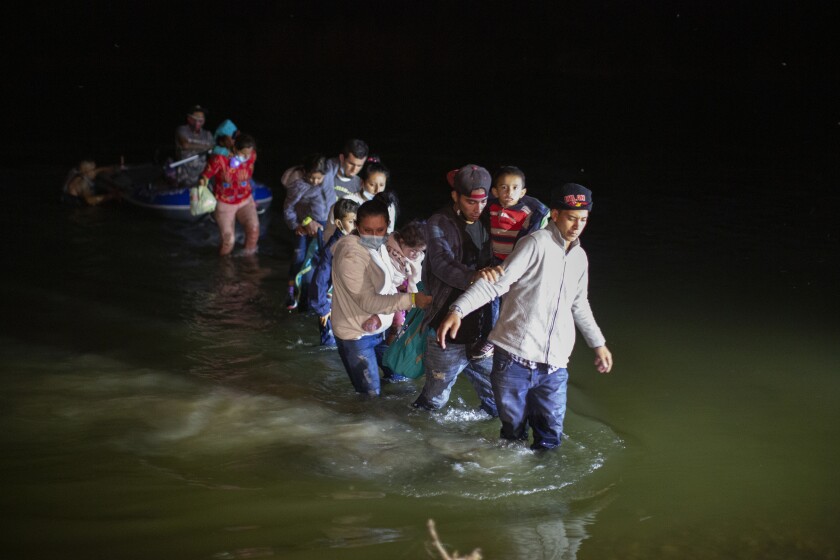 FILE - Migrant families wade through shallow waters toward Roma, Texas, March 24, 2021. President Joe Biden took office on Jan. 20, 2022, and almost immediately, the numbers of migrants exceeded expectations. While specific reports are isolated, widespread extortion in Central America explains why many seek asylum in the United States in the first place and some advocates fear prospects of a large payment will fuel many more threats. (AP Photo/Dario Lopez-Mills, File)