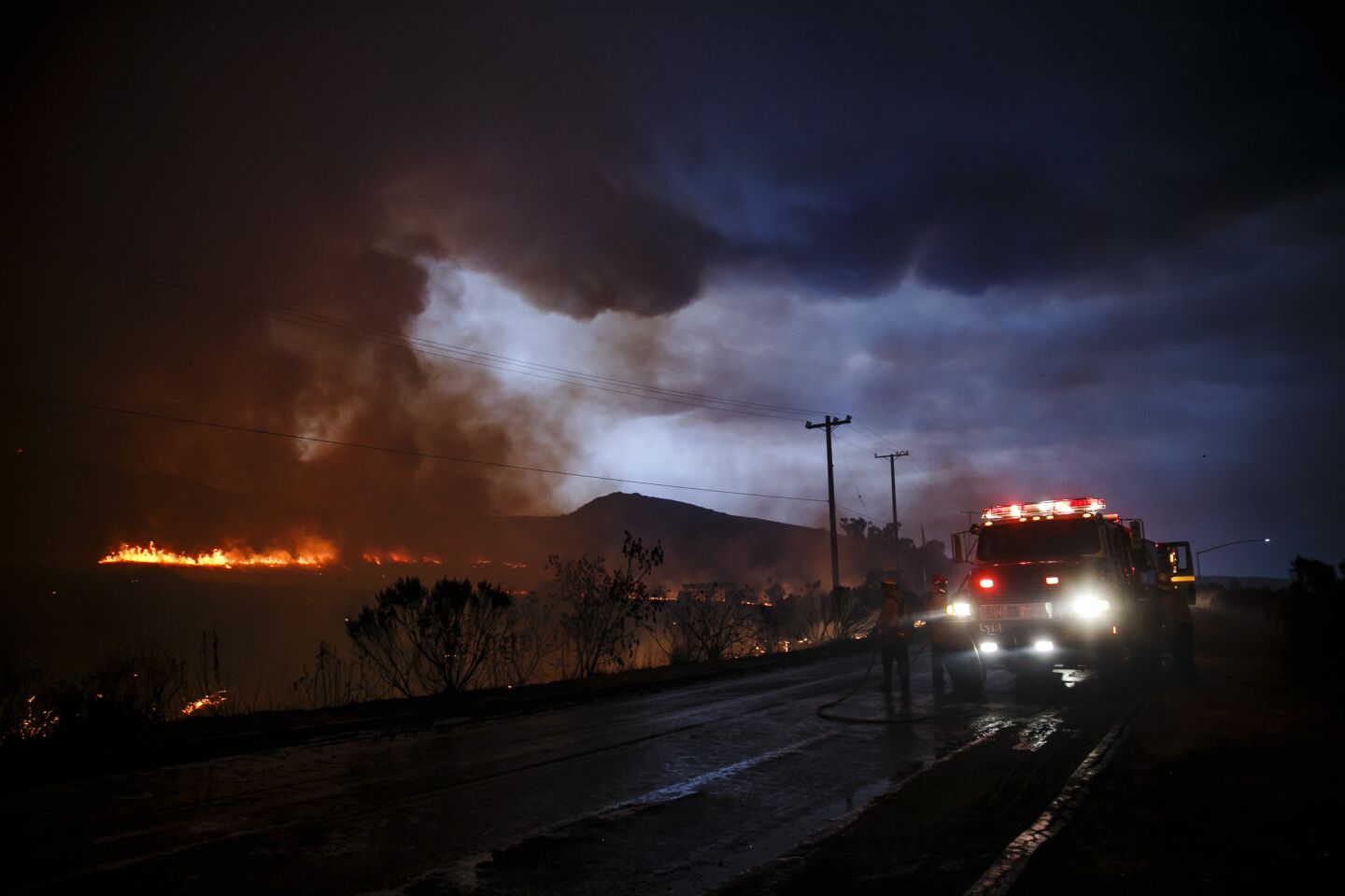 Firefighters make a defensive move on the front lines of the Sherpa Fire to avoid it from moving onto the 101 freeway, along Calle Real road, in Goleta, Calif.,