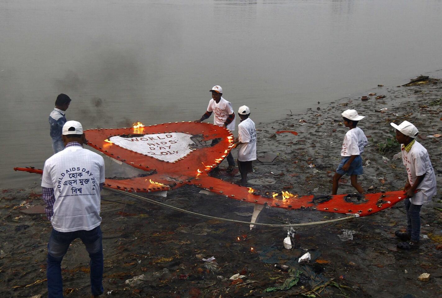 Activists from an NGO carry a giant red ribbon lit with oil lamps before releasing it in the waters of the river Ganges during an HIV/AIDS awareness campaign to mark World AIDS Day in Kolkata