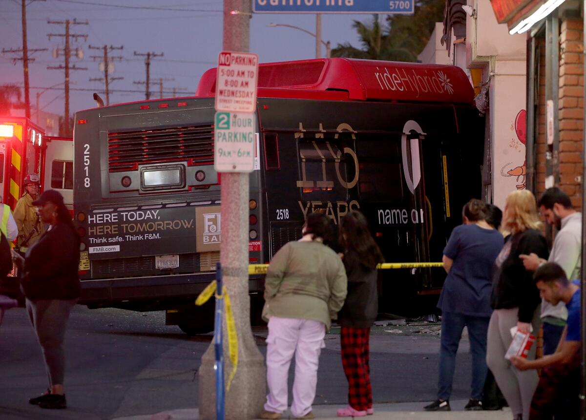 People and a firetruck are seen near a bus that has crashed into the side of a building.