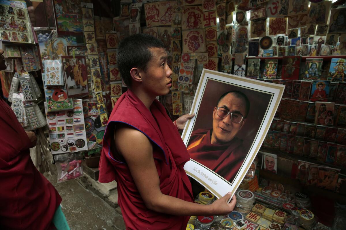 A young monk looks at a poster of the Dalai Lama at a sidewalk stand in Dharamsala, India, on March 10, 2014.