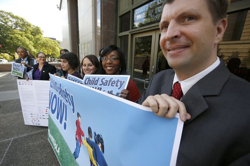 Social worker David Green (right) and members of United Voices for Children and Families, a coalition of labor and child welfare advocates, testified before Los Angeles County's Blue Ribbon Commission on Child Protection at the Hall of Administration, hold up a banner proclaiming CHILD SAFTEY NOW!