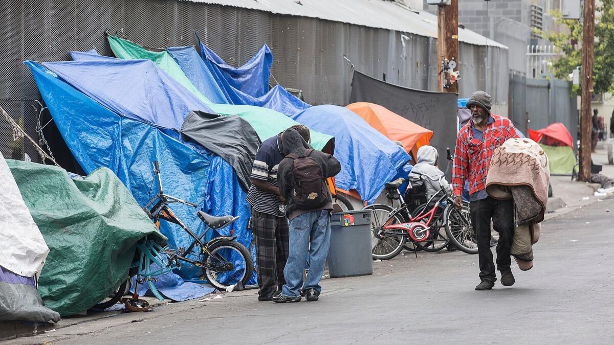 Homeless people gather near tents on L.A.'s Skid Row at San Julian and 6th Streets.