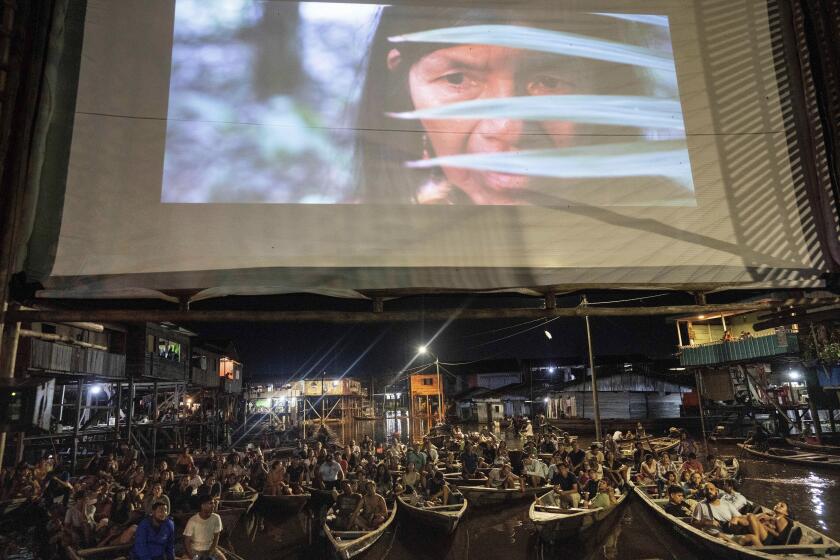 Spectators watch from boats a film projected on a screen set up on a wooden structure during the Muyuna Floating Film Festival, that celebrares tropical forests, in the Belen neighborhood of Iquitos, Peru, Saturday, May 25, 2024. (AP Photo/Rodrigo Abd)