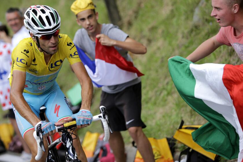 A fan (right) waves an Italian flag as stage winner and overall leader Vincenzo Nibali climbs toward Hautacam during the eighteenth stage of the Tour de France on Thursday.