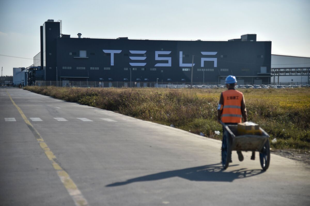 A worker walks on a road next to the new Tesla factory built in Shanghai.