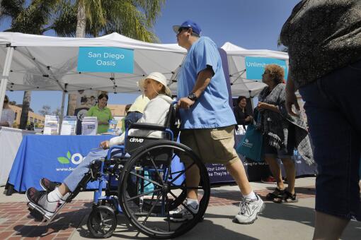 SAN DIEGO, CA 6/9/2018: Hector Gomez, right, of Skyline, a caregiver for his mother, Delores Gomez, eft, pusher her past the booths during the CaregiverSD Community Expo at Liberty Station. Photo by Howard Lipin/San Diego Union-Tribune/Mandatory Credit: HOWARD LIPIN SAN DIEGO UNION-TRIBUNE/ZUMA PRESS